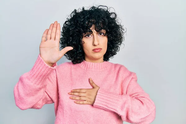 Young middle east woman wearing casual clothes swearing with hand on chest and open palm, making a loyalty promise oath