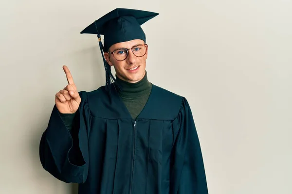 Young Caucasian Man Wearing Graduation Cap Ceremony Robe Showing Pointing — Φωτογραφία Αρχείου