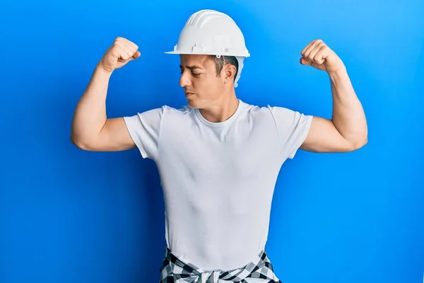 Handsome Young Man Wearing Builder Uniform Hardhat Showing Arms Muscles — 스톡 사진