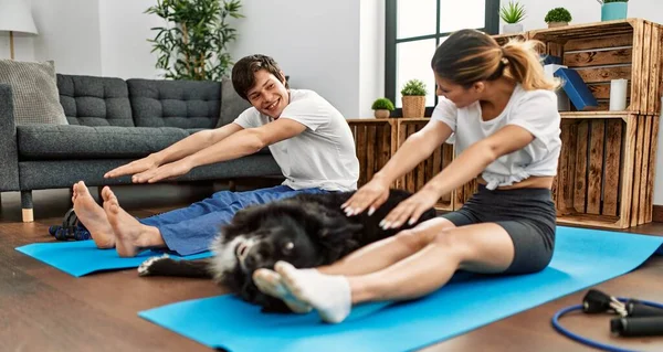 一对年轻的高加索夫妇笑着高兴地在家里用狗训练瑜伽 — 图库照片