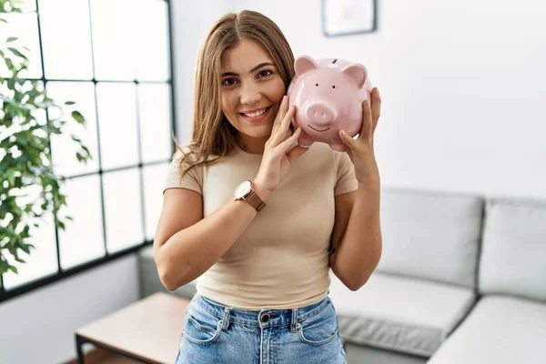 Joven Mujer Hispana Sonriendo Confiada Sosteniendo Piggybank Casa —  Fotos de Stock