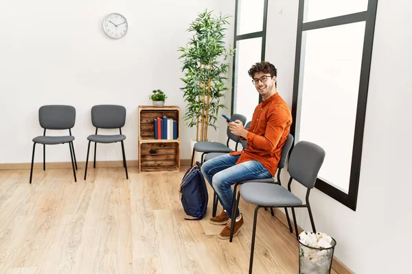 Young Hispanic Man Smiling Confident Using Smartphone Waiting Room — Stockfoto
