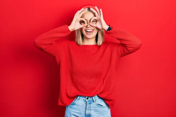 Beautiful Blonde Woman Wearing Casual Red Sweater Doing Gesture Binoculars — Stockfoto