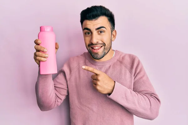 Jonge Spaanse Man Met Shampoo Fles Glimlachend Vrolijk Wijzend Met — Stockfoto