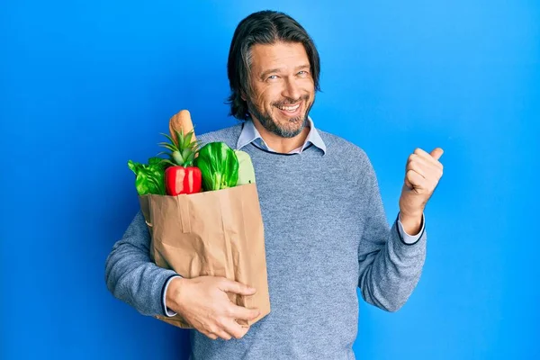Hombre Guapo Mediana Edad Sosteniendo Bolsa Papel Con Comestibles Apuntando —  Fotos de Stock