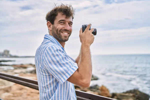 Fiatal Spanyol Férfi Mosolyog Boldog Segítségével Fényképezőgép Strandon — Stock Fotó