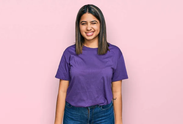 若いですヒスパニック女の子身に着けていますカジュアル紫Tシャツウインク見ますザ カメラとともにセクシー表現 陽気で幸せな顔 — ストック写真