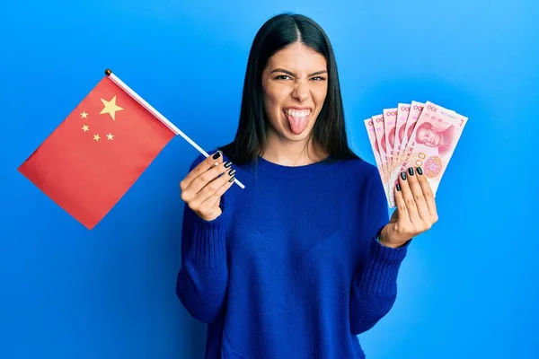 Νεαρή Ισπανόφωνη Γυναίκα Κινεζική Σημαία Και Χαρτονομίσματα Γιουάν Βγάζουν Γλώσσα — Φωτογραφία Αρχείου