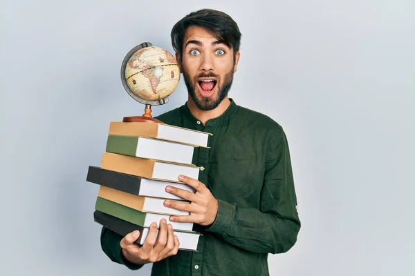 Young Hispanic Man Holding Books World Ball Celebrating Crazy Amazed — Fotografia de Stock