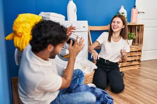 男男女女笑着自信地在洗衣房里玩耍清洁衣服 — 图库照片