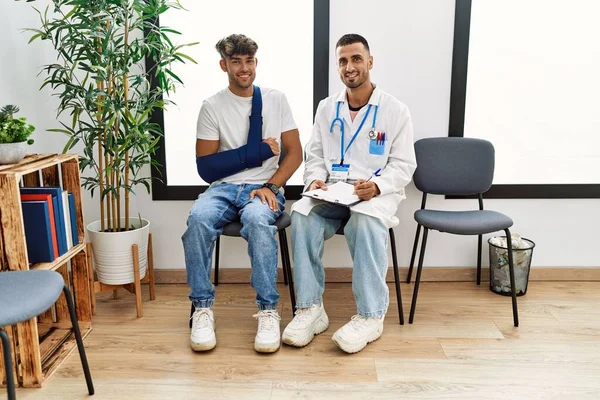 Zwei Hispanische Männer Arzt Und Patient Schreiben Auf Klemmbrett Sitzt — Stockfoto