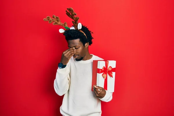 Young African American Man Wearing Deer Christmas Hat Holding Gift — Fotografia de Stock