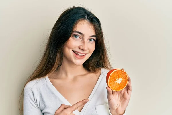 Young Caucasian Woman Holding Fresh Slice Orange Smiling Happy Pointing — стоковое фото