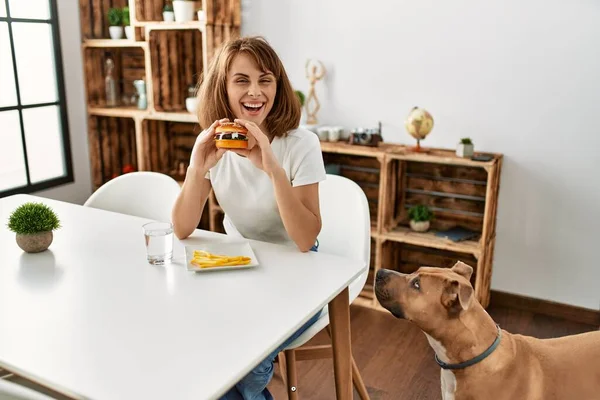 Mladý Kavkazský Žena Jíst Klasický Hamburger Sedí Stole Doma — Stock fotografie