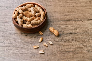 Tahta bir masada kasedeki fıstık demeti.