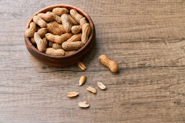 Tahta bir masada kasedeki fıstık demeti.