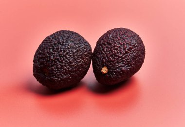  Kırmızı zemin üzerinde iki avokado meyvesi