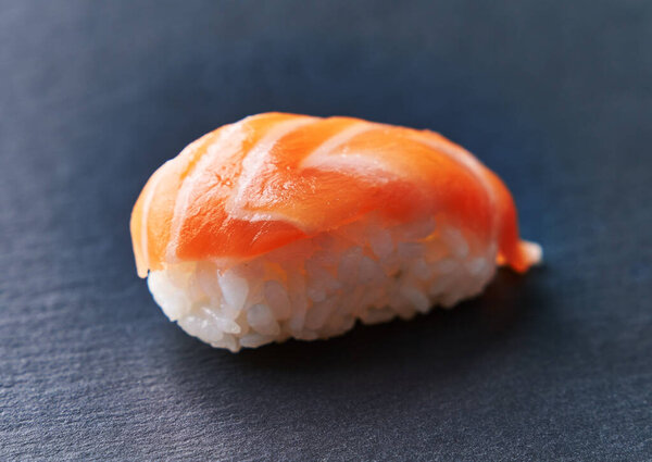  Single salmon nigiri sushi on a blackboard surface