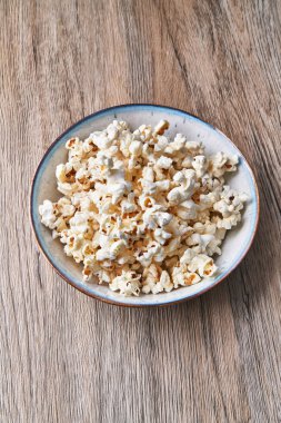  Tahta bir yüzeyde bir kase tuzlu patlamış mısır.