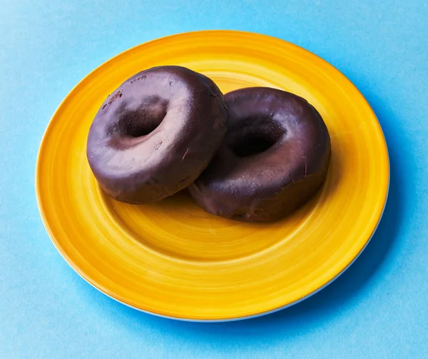  Plate of two chocolate doughnuts on a blue background