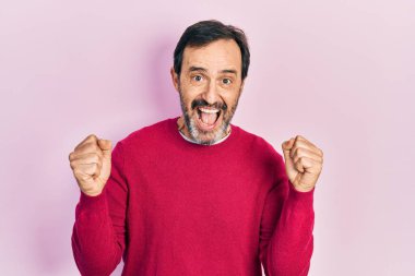 Orta yaşlı İspanyol bir adam gündelik giysiler giyip kollarını kaldırıp, gözleri açık bir şekilde başarıyı kutluyor. Kazanan konsept. 