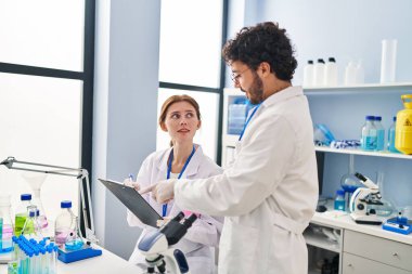 Erkek ve kadın bilim adamları laboratuarda çalışıyor.