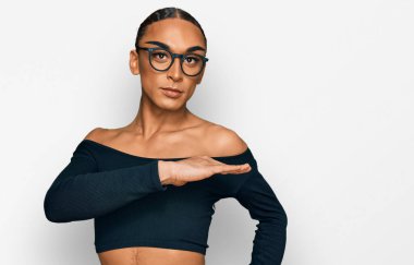 Hispanic transgender man wearing make up and long hair wearing women clothes gesturing with hands showing big and large size sign, measure symbol. smiling looking at the camera. measuring concept. 