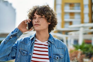 Genç İspanyol adam şehirde telefonla konuşuyor.