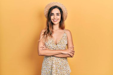 Yazlık şapka takan, kollarını kavuşturup kameraya gülümseyen genç İspanyol kız. pozitif kişi. 