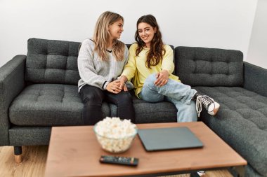 Mutlu gülümseyen genç çift evdeki kanepede oturuyor..