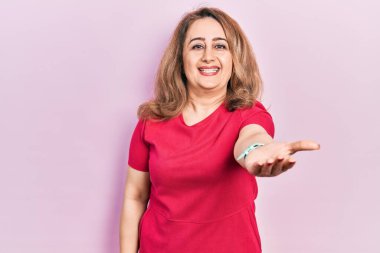 Orta yaşlı, günlük kıyafetler giyen, neşeli gülümseyen, yardım eli uzatan ve kabul gören beyaz bir kadın.. 