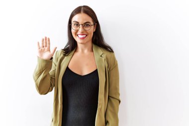 Genç esmer kadın izole edilmiş arka planda duruyor. Mutlu ve güler yüzlü bir şekilde selam veriyor. Hoş geldin jesti. 