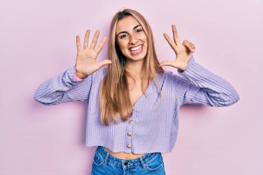 Gündelik tişört giyen güzel İspanyol kadın gülümseyerek kendinden emin ve mutlu bir şekilde sekiz numarayı gösteriyor ve işaret ediyor.. 