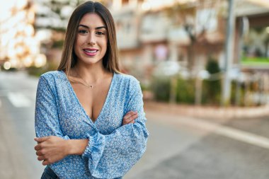 Genç İspanyol kadın şehirde kolları bağlı mutlu gülümsüyor..