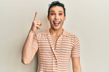 Handsome man wearing make up wearing casual t shirt pointing finger up with successful idea. exited and happy. number one. 