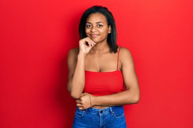 Kolsuz tişörtlü, sıradan giyinen genç Afro-Amerikalı kız kameraya kollarını kavuşturup gülümseyerek bakıyor ve çenesini kaldırıyor. Olumlu düşünmek. 
