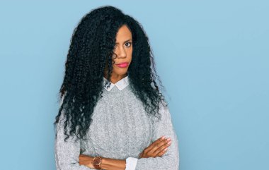 Orta yaşlı Afro-Amerikalı kadın gündelik kıyafetler giyiyor şüpheci ve gergin, yüzünde çapraz kollarla onaylamayan bir ifade. negatif kişi. 