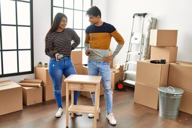 Genç Latin çift gülümsüyor mutlu mobilyaları yeni evlerinde birleştiriyorlar..