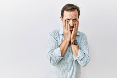 Middle age hispanic man with beard standing over isolated background tired hands covering face, depression and sadness, upset and irritated for problem 