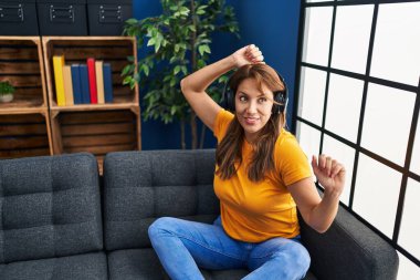 Evdeki kanepede oturmuş müzik dinleyen genç Latin kadın.