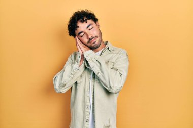 Gündelik kıyafetler giyen genç İspanyol adam uyur. Yorgun düşler kurar, ellerle poz verir, gözleri kapalı gülümserdi.. 