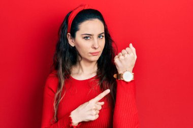 Gündelik kıyafetler giyen genç İspanyol kadın saati, sabırsızlığı ve rahat bir ifadeyle kameraya bakmayı işaret ediyor. 