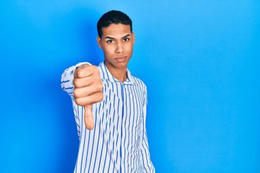 Young african american guy wearing casual clothes looking unhappy and angry showing rejection and negative with thumbs down gesture. bad expression. 