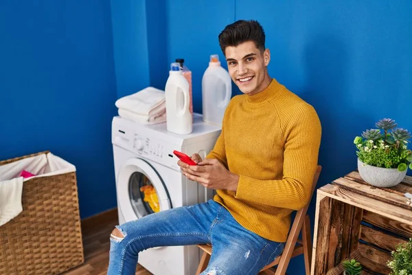 Jonge Spaanse Man Met Smartphone Wachtend Wasmachine Bij Wasserij — Stockfoto