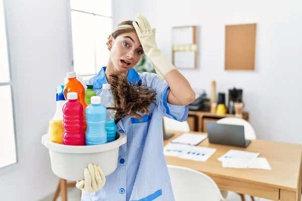 Young Blonde Woman Wearing Cleaner Uniform Holding Cleaning Products Surprised — Stok fotoğraf
