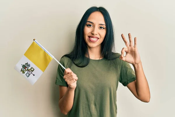 Young Hispanic Girl Holding Vatican City Flag Doing Sign Fingers — Stockfoto