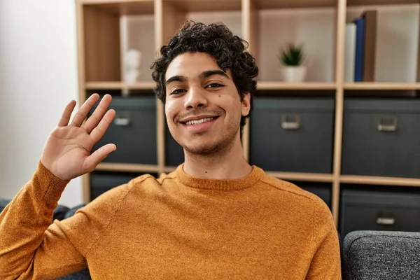 Ung Latinamerikansk Man Ler Glad Säger Hej Sitter Soffan Hemma — Stockfoto