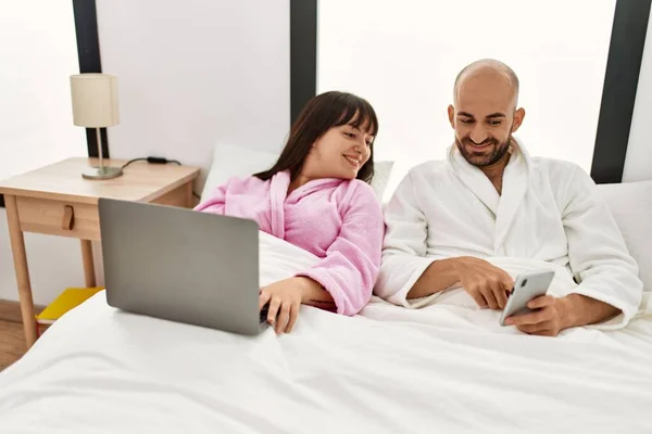 Jovem Casal Hispânico Usando Laptop Smartphone Sentado Cama Quarto — Fotografia de Stock