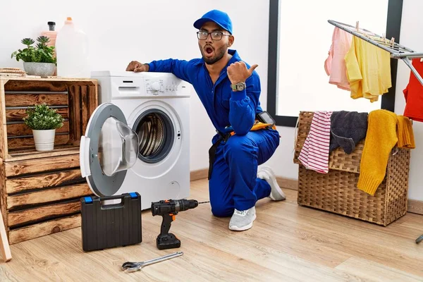 Young Indian Technician Working Washing Machine Surprised Pointing Hand Finger — Stok fotoğraf