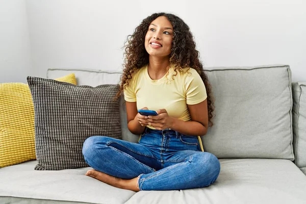 Genç Latin Kadın Evde Akıllı Telefon Kullanarak Kendine Güvenerek Gülümsüyor — Stok fotoğraf